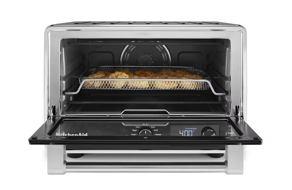 Hands adjusting the temperature dial on a modern air fryer to control cooking settings.