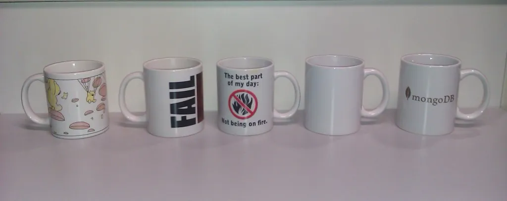 Four coffee mugs of increasing sizes lined up on a white marble countertop.