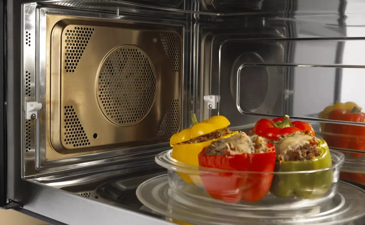 A metal baking pan and a non-metallic pan beside a convection microwave oven.