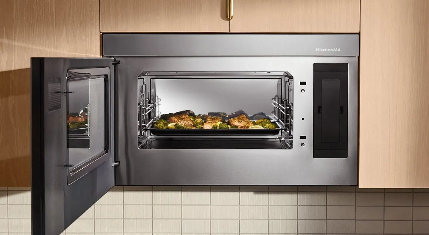 An open convection microwave oven showing a roasted chicken inside on a plate.